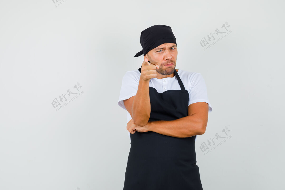 男人面包师穿着t恤 围裙指着摄像机 看起来很生气成人职业前台