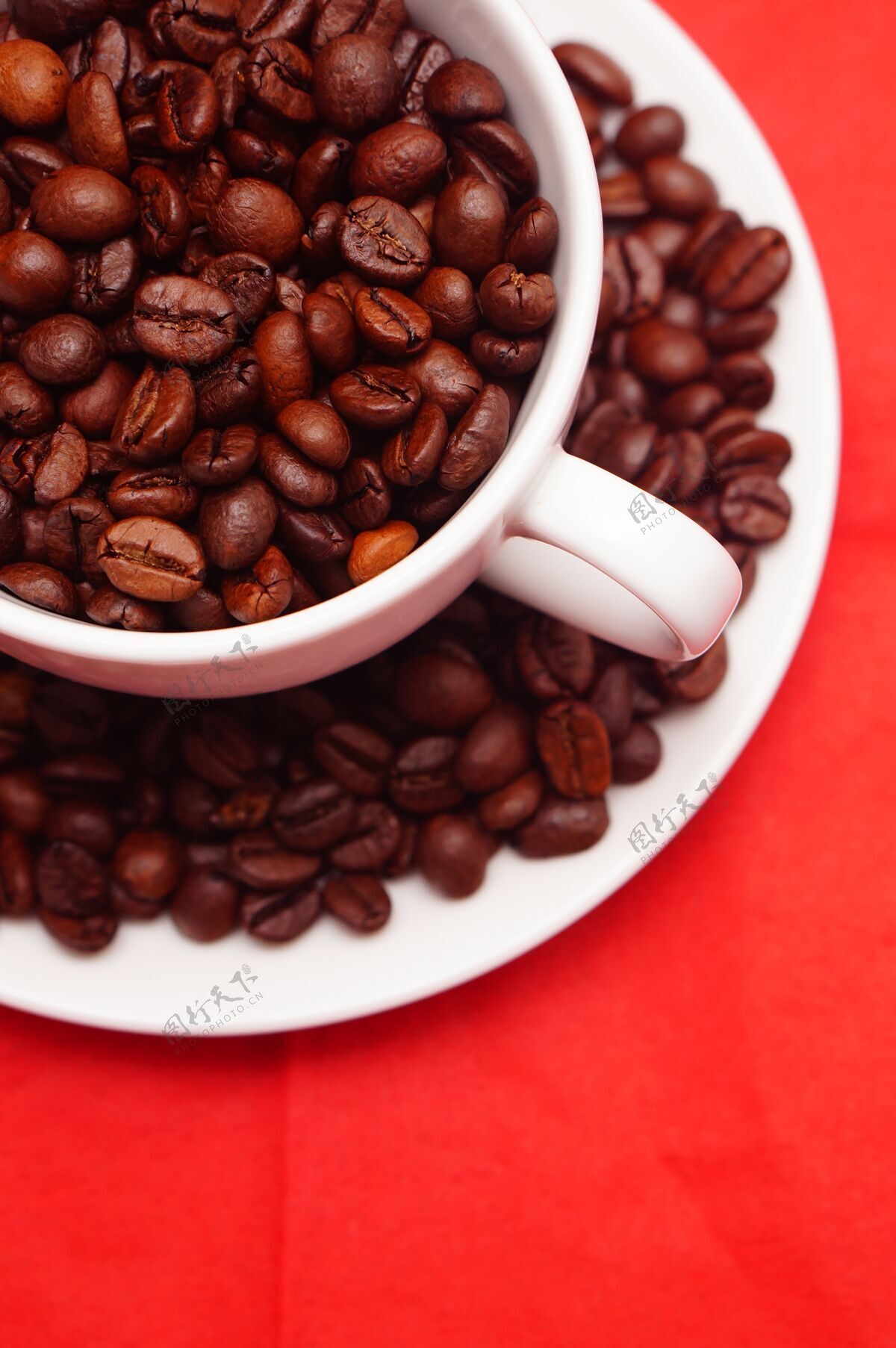 咖啡垂直特写镜头一个白色的杯子装满了新鲜的咖啡豆放在红色的桌子上饮料咖啡馆深色