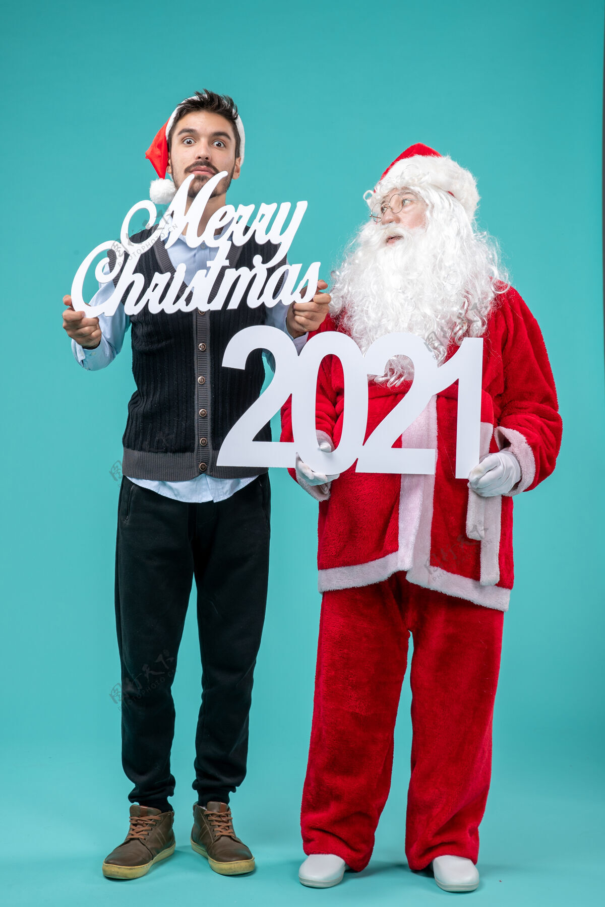 新前视图圣诞老人与年轻的男性举行圣诞快乐和蓝色背景上的作品蓝色圣诞景色