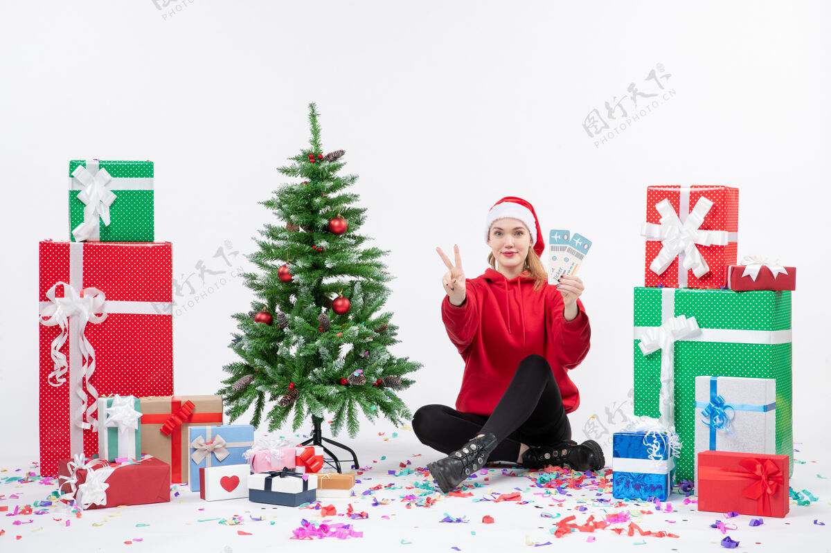 周围前视图年轻女子围坐在白墙上拿着飞机票的礼物圣诞快乐礼物节日