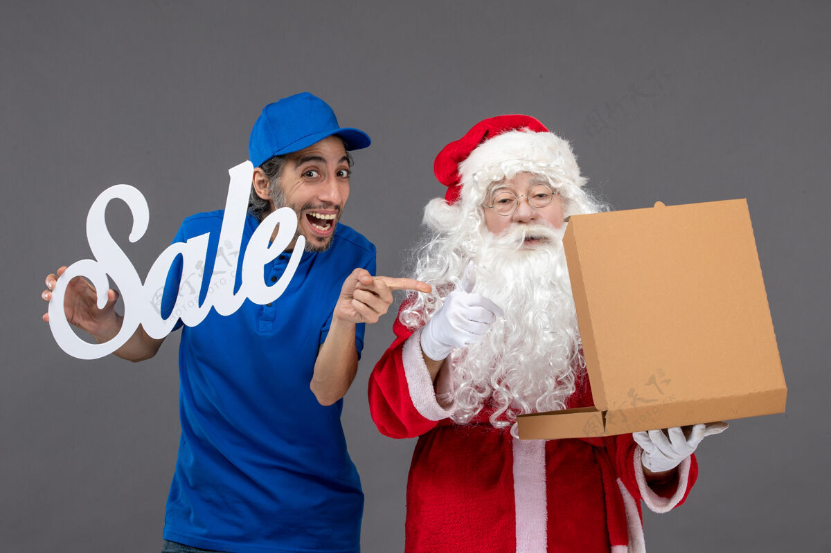 十二月圣诞老人的正面图 男信使手持销售横幅 打开灰墙上的食品盒圣诞老人圣诞节快递