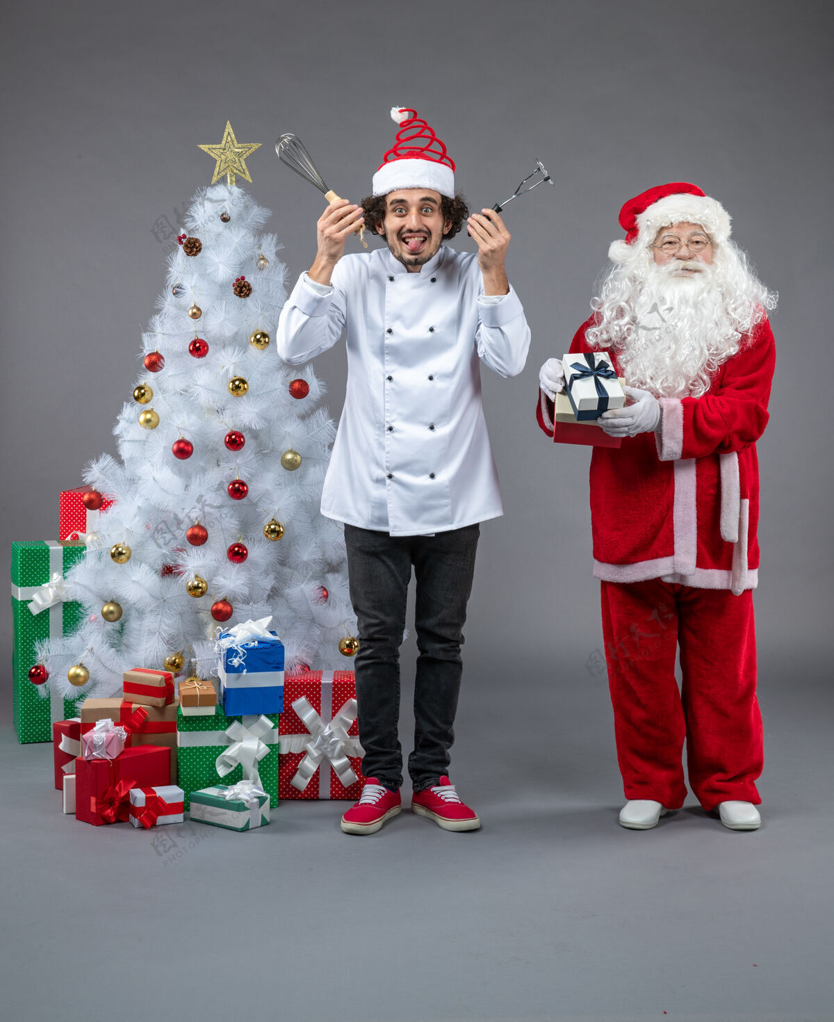 庆祝圣诞老人和男厨师在灰色墙上围着圣诞礼物的正视图人节日圣诞