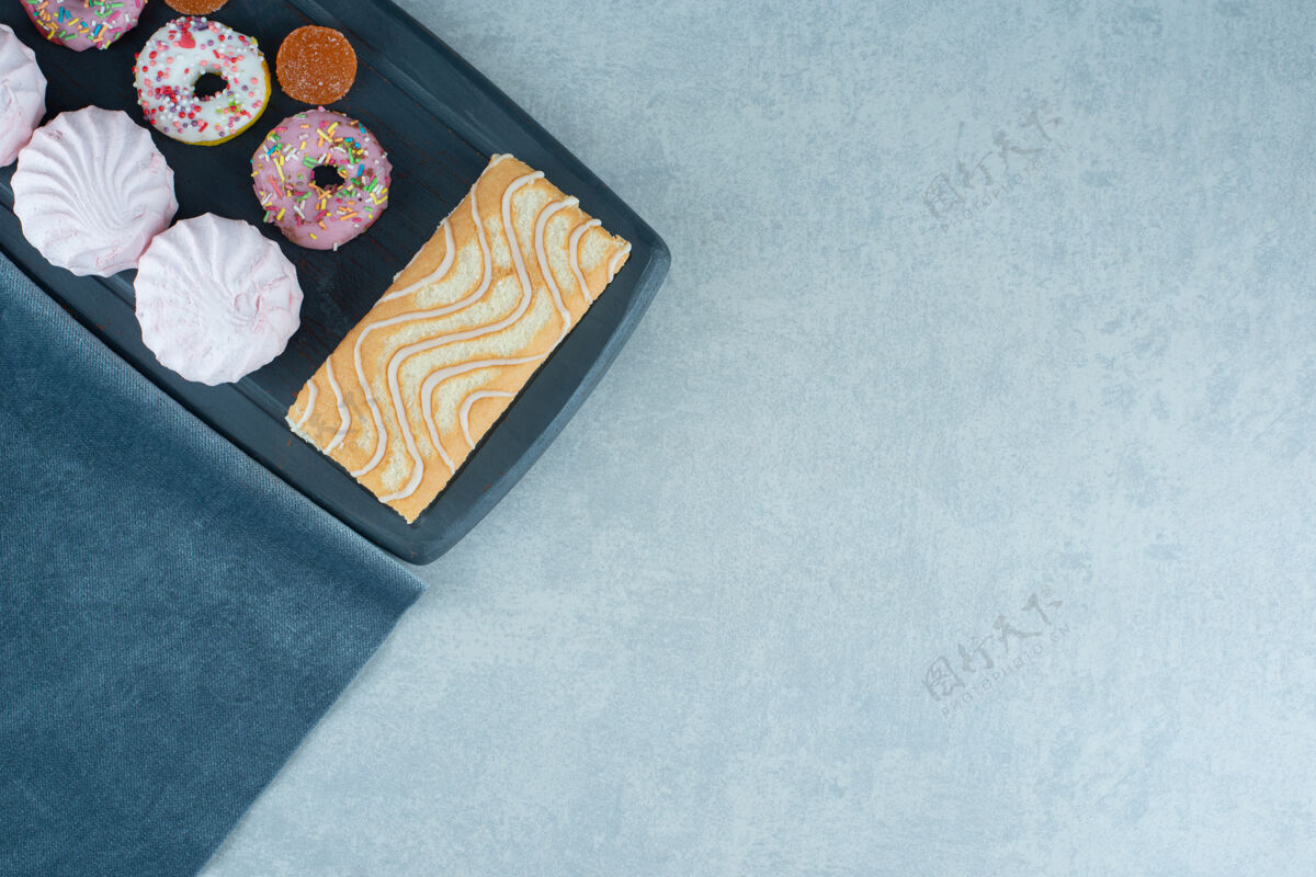 烘焙蛋糕卷 饼干 甜甜圈和marmelades放在一块海军蓝的大理石板上饼干甜点烘焙食品