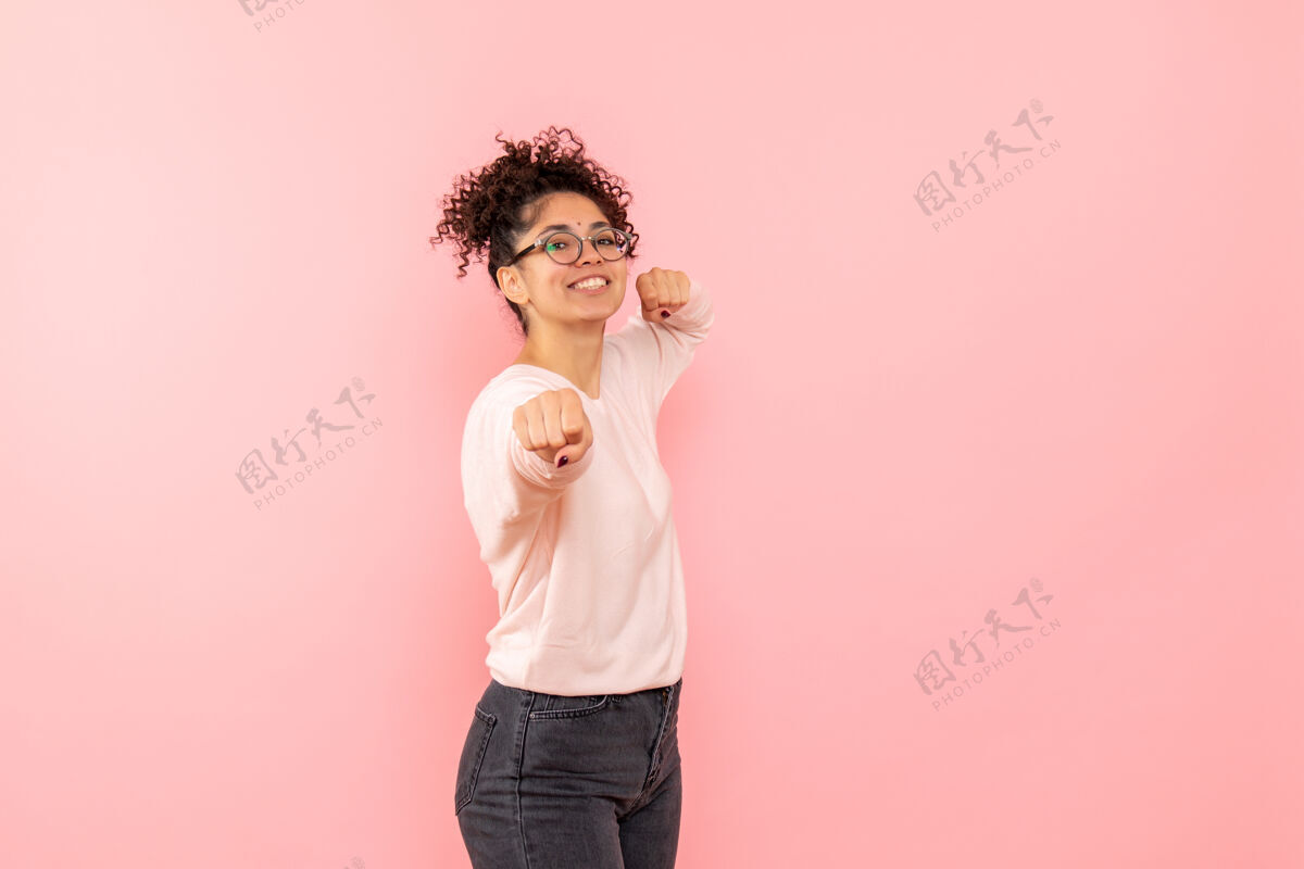 年轻女性年轻女子在粉红色墙上微笑着摆姿势的正面图肖像摆姿势微笑