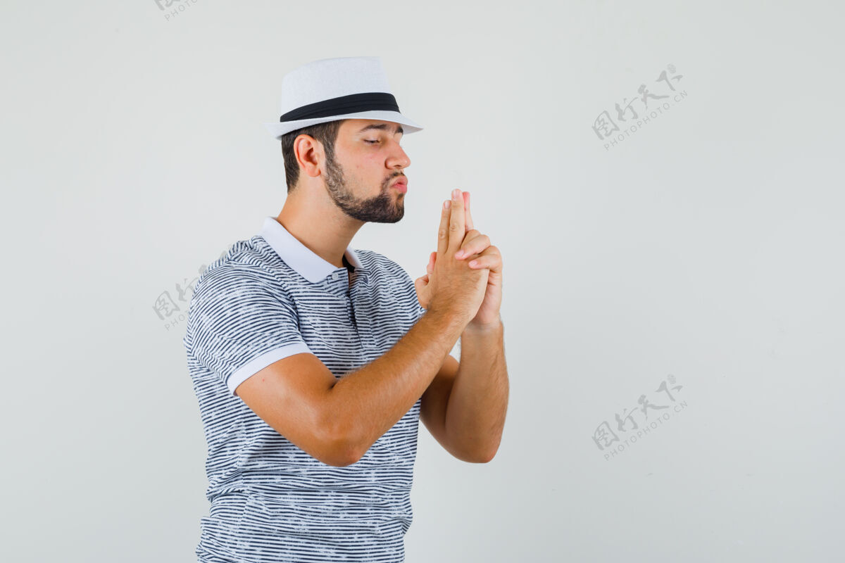 帅气一个年轻人穿着条纹t恤 戴着帽子 做着射击枪的姿势 看上去很专注正视图成人模特工作室