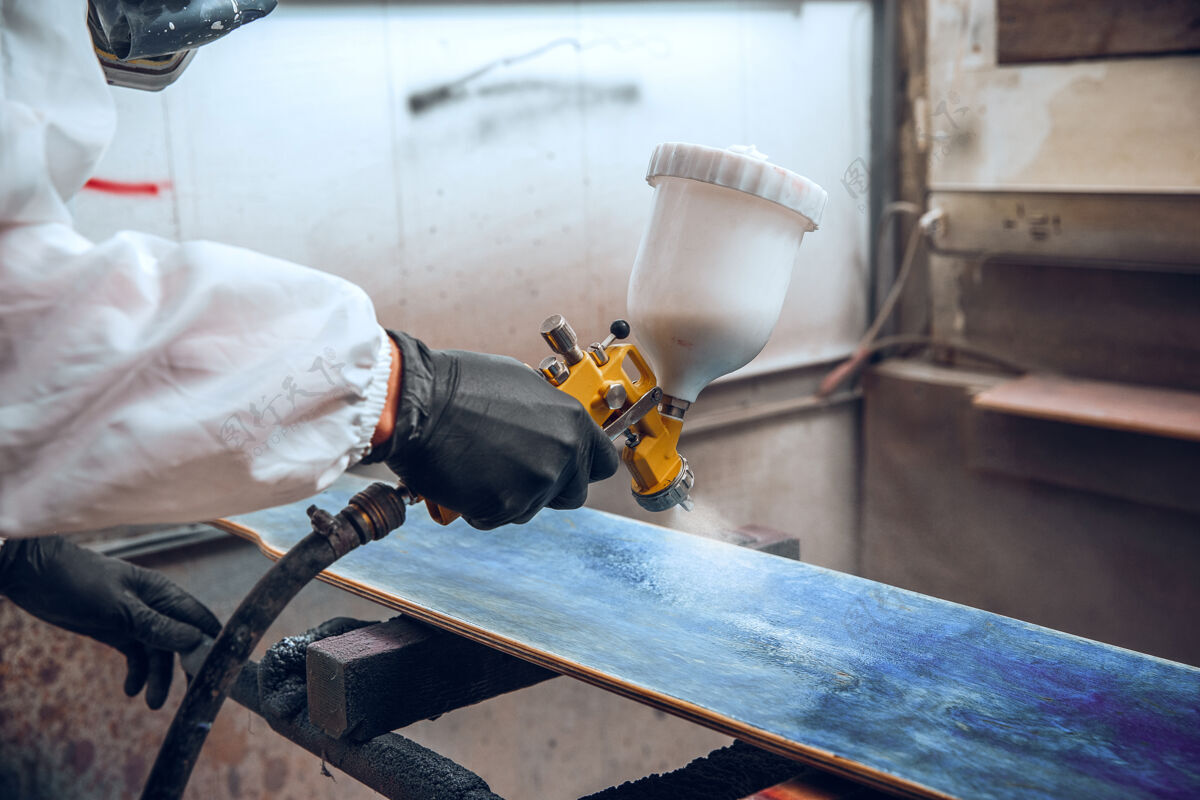 车间一家工厂的油漆大师-用喷枪对木头进行工业油漆木工喷涂木材