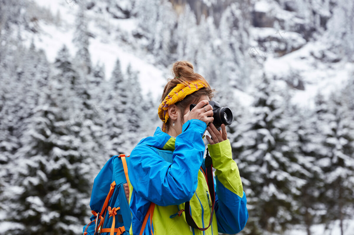 雪女性远足者在雪山中的水平视图 到达山顶 从山上用相机拍照山娱乐照片