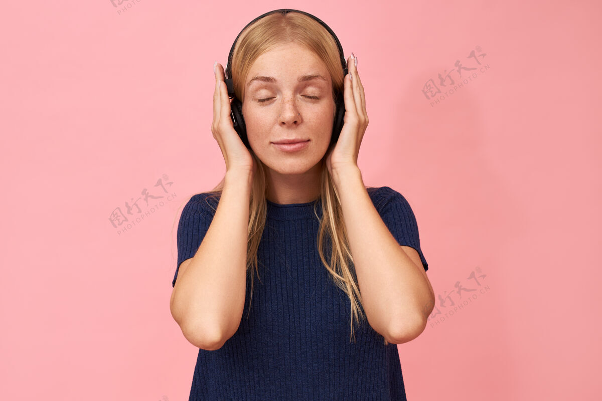 乐趣可爱的年轻白种人 长着雀斑 闭着眼睛 用无线耳机欣赏她最喜欢的音乐艺术家的新专辑女人可爱脸庞