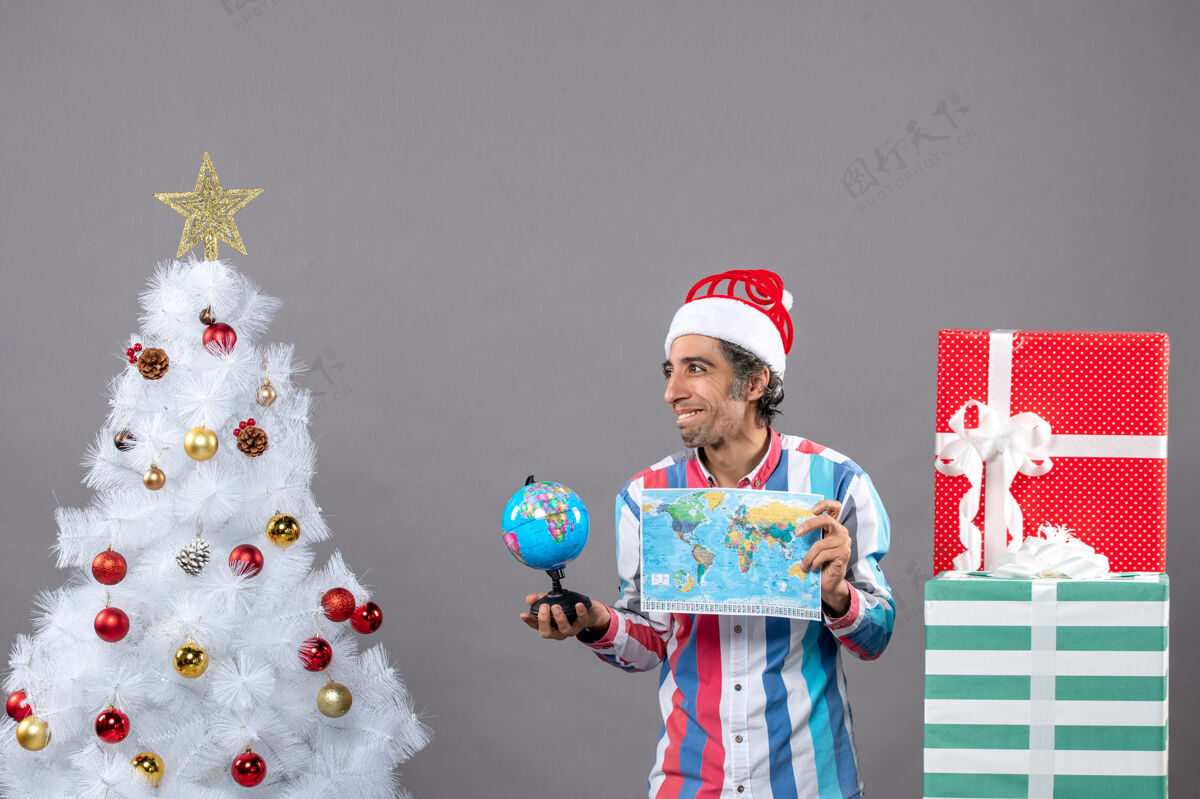 人前视图满意的人拿着世界地图和地球仪圣诞树成人圣诞
