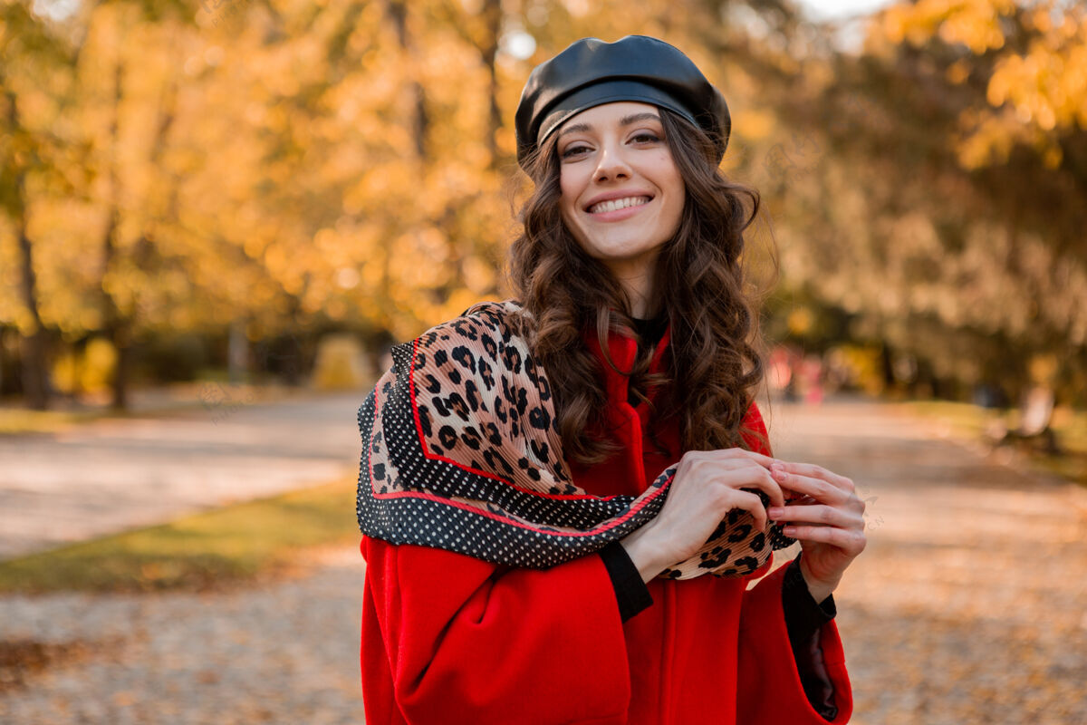 女孩迷人时尚微笑的女人卷发漫步在公园穿着暖红色外套秋季时尚 街头风格 戴贝雷帽和豹纹围巾魅力配饰户外