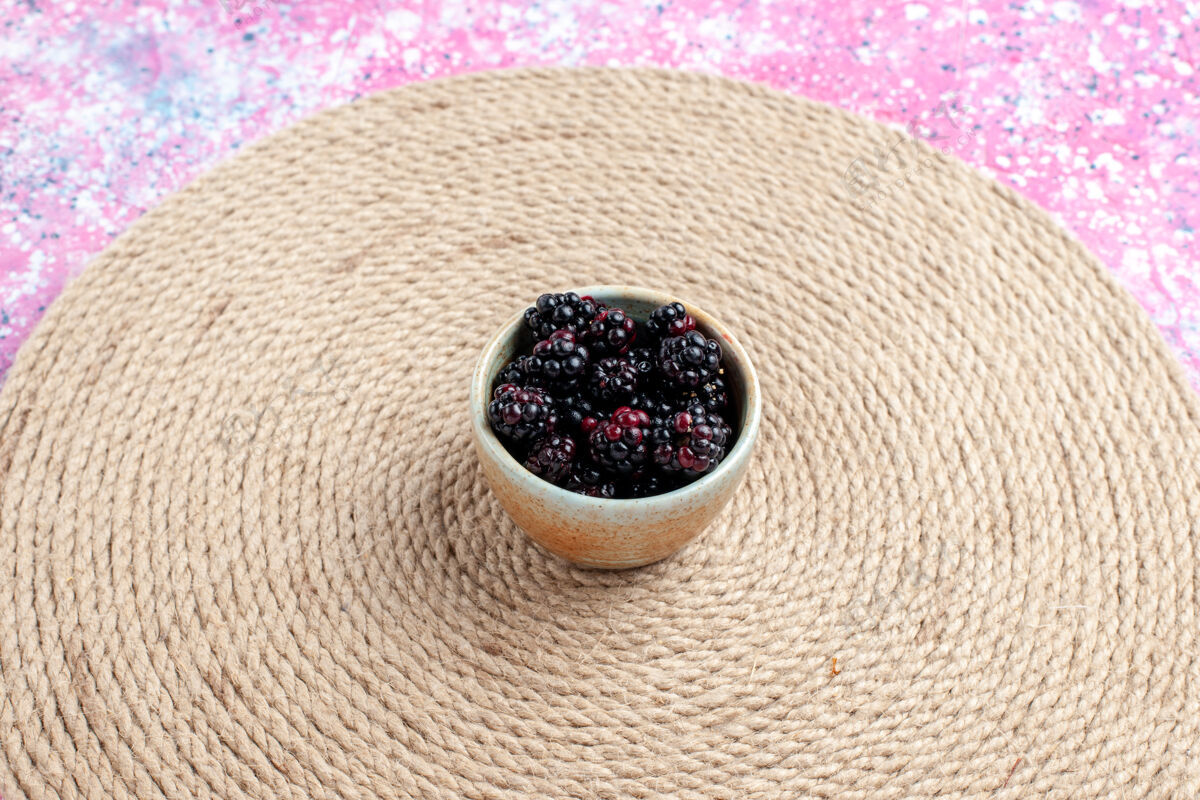 织物在粉红色桌子上的小罐子里看到新鲜的黑莓大麻前面粗麻布