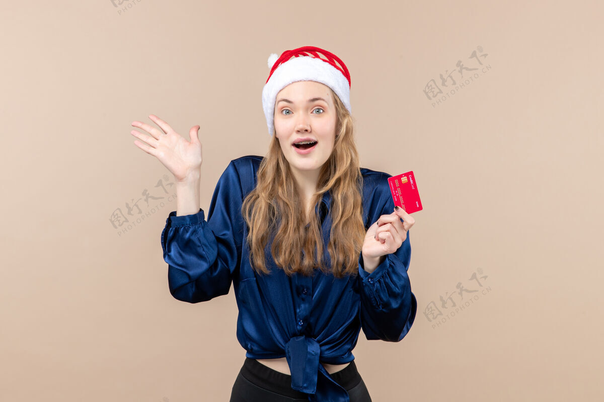 微笑正面图年轻女性手持粉色背景的红色银行卡圣诞钱合影过年感慨微笑女性抱着