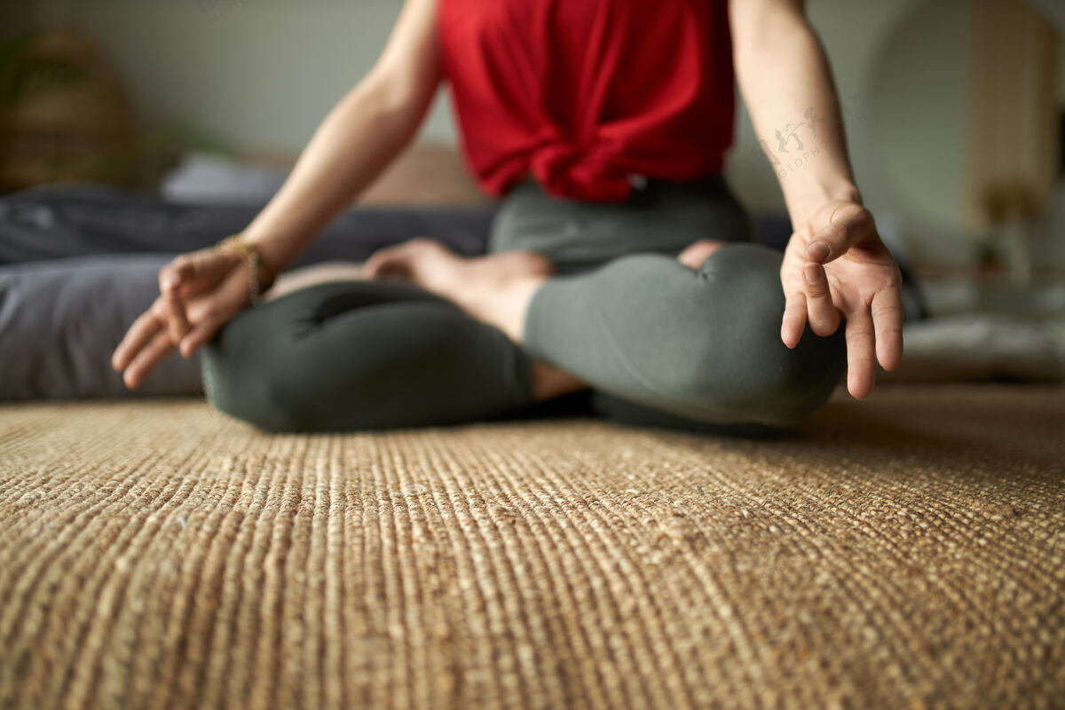 冥想赤脚女人的剪短肖像 穿着紧身裤 以莲花的姿势坐在地毯上练习冥想以减轻压力享受年轻活动