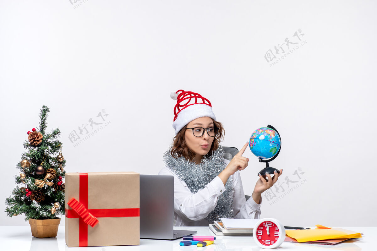 地球仪正面图：年轻的女工坐在她拿地球仪的地方前面 背景是白色的办公室地球仪风景