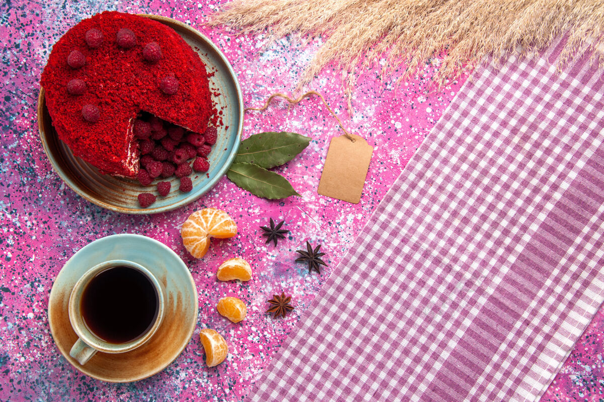 桌子红色覆盆子蛋糕的顶视图 粉红色的表面上有橘子和茶饼干糖蛋糕