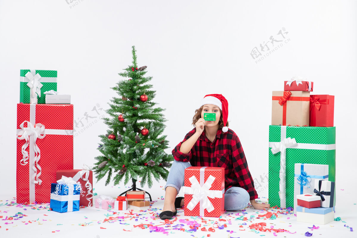 礼物前视图年轻女子围坐在一个白色的墙上拿着绿色银行卡的礼物坐着前面银行