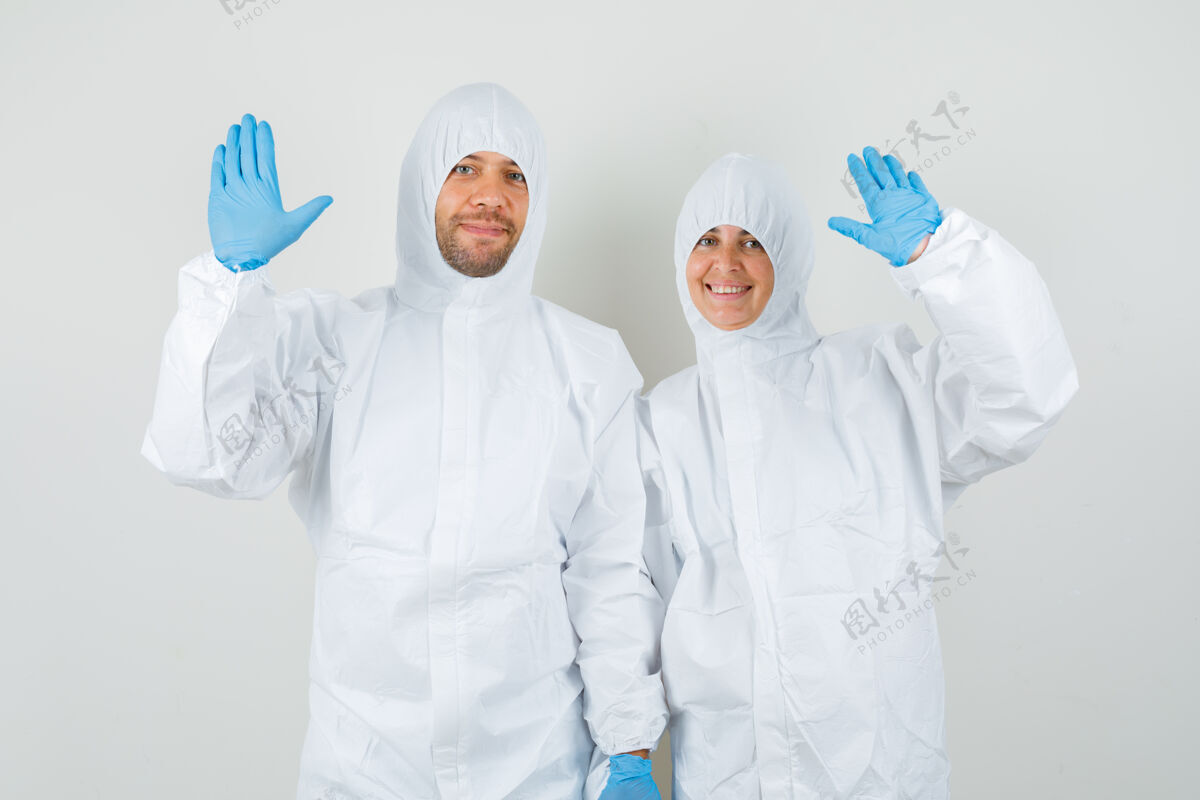 手两个穿着防护服的医生挥手打招呼或告别护理制服女