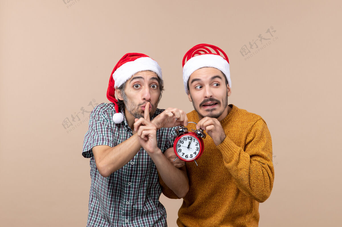 米色正面图两个男人都拿着红色的钟 一个在米色背景上做嘘标志脸两个男人男性