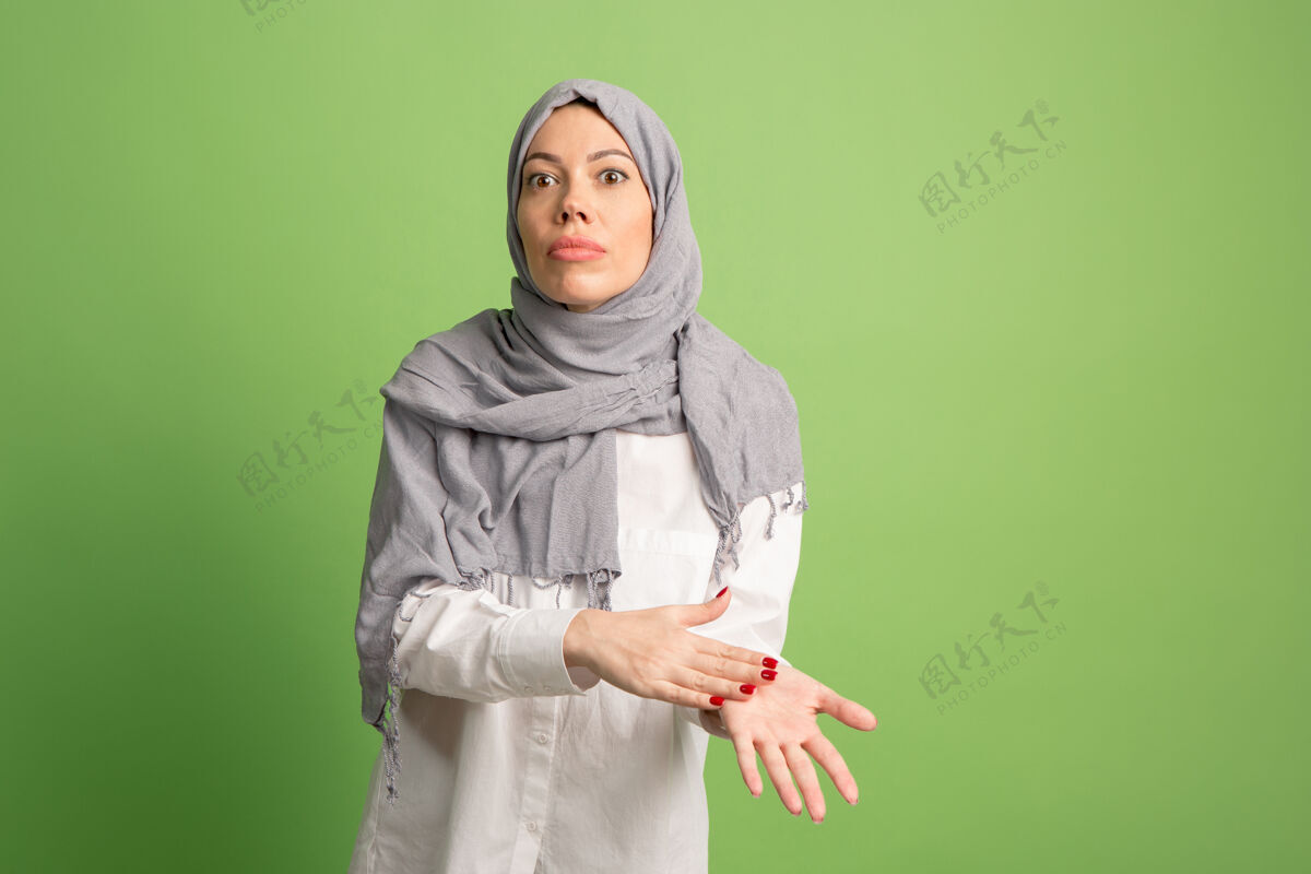 争论争论 争论概念戴头巾的阿拉伯女人女孩肖像 在绿色工作室背景摆姿势年轻情绪化的女人人类情绪 面部表情概念正面视图女性亚洲人伊斯兰
