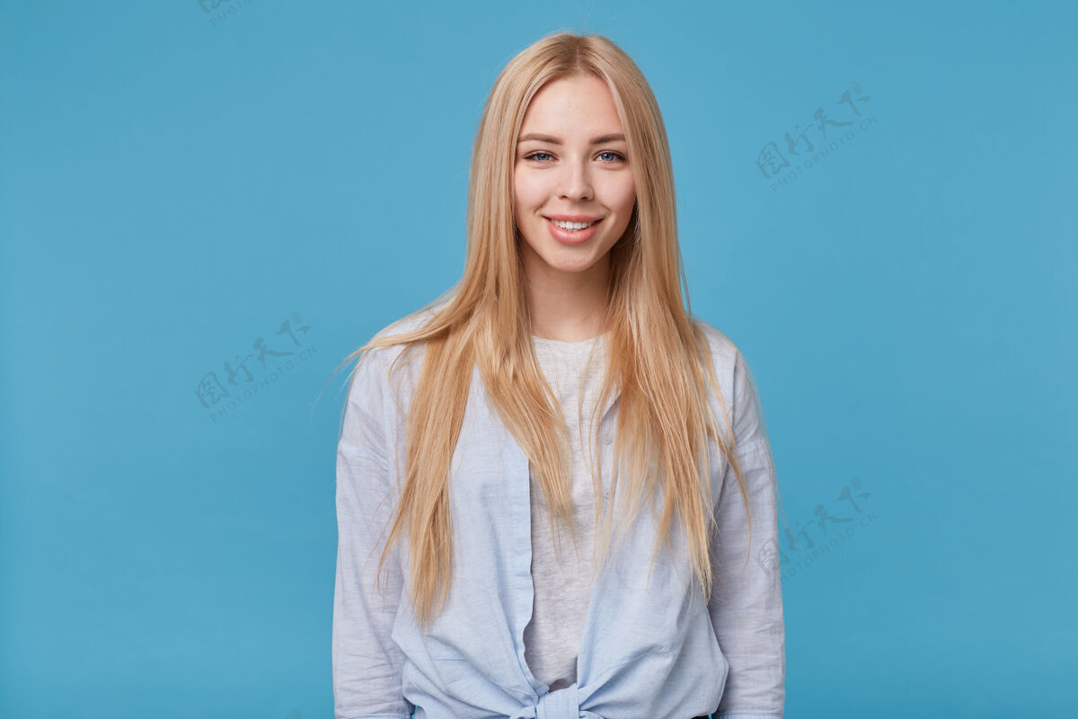 站着年轻的金发美女的肖像 留着长长的头发 穿着蓝色衬衫和灰色t恤 手放在地上 面带迷人的微笑宽快乐自然