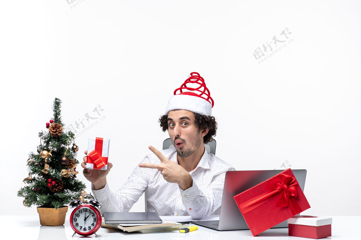 帽子圣诞节心情搞笑兴奋情绪激动的年轻商人圣诞老人帽子 并指出他的礼物在白色背景礼物兴奋指着