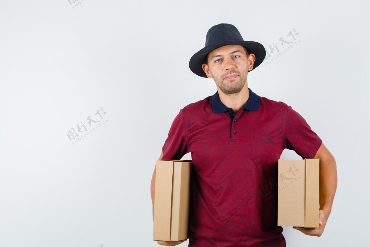 帅气穿红衬衫 戴黑帽子的年轻男子 手拿箱子 正面视图长相年轻休闲