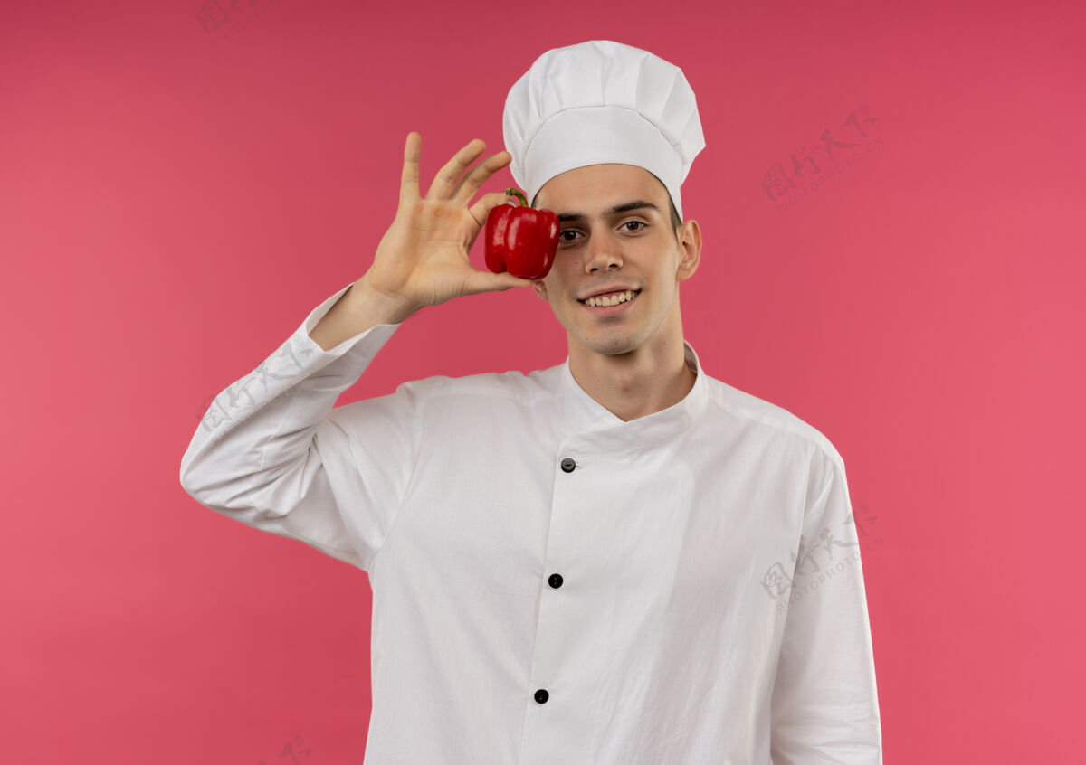 胡椒粉面带微笑的年轻男厨师穿着厨师制服 眼睛周围拿着胡椒粉拿着厨师厨师