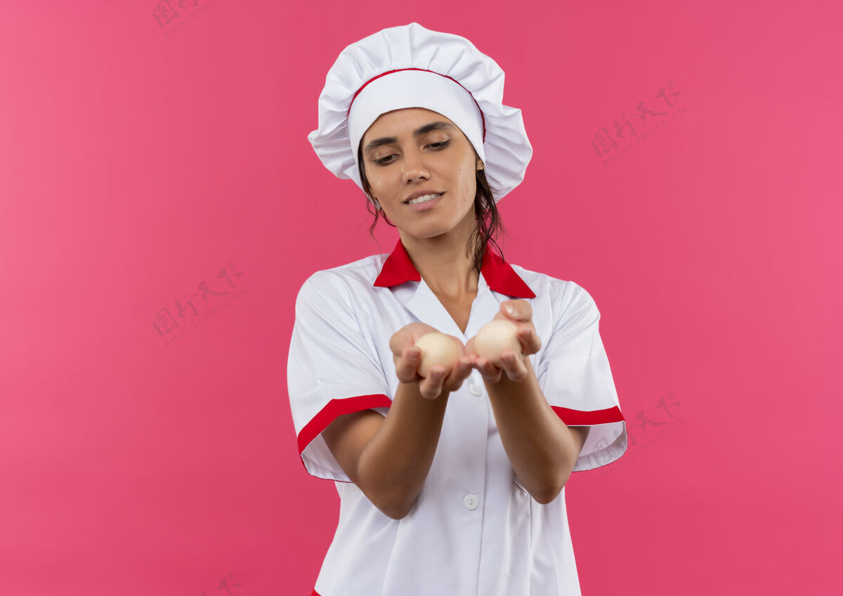 女高兴的年轻女厨师穿着厨师制服拿着鸡蛋对着镜头用复印空间厨师鸡蛋高兴