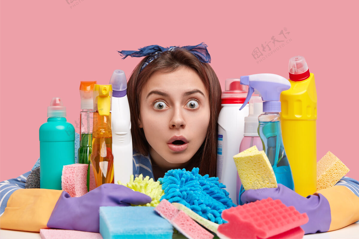 清洁家庭观念惊呆了的黑发女人盯着一瓶瓶洗碗液 用洗涤剂做微波炉和炉子化学品惊呆Omg