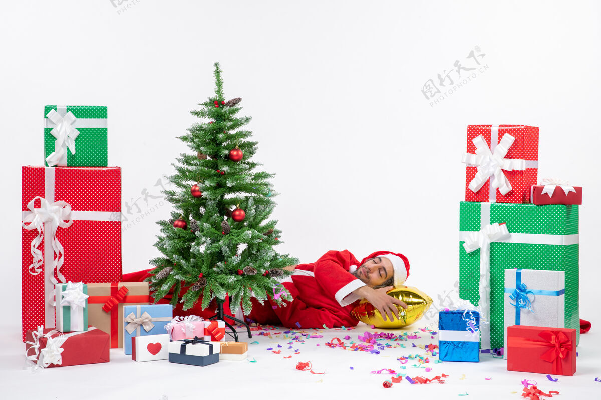 圣诞树圣诞老人躺在圣诞树后面 在不同颜色的礼物旁边 白色背景的股票照片礼物圣诞老人礼物