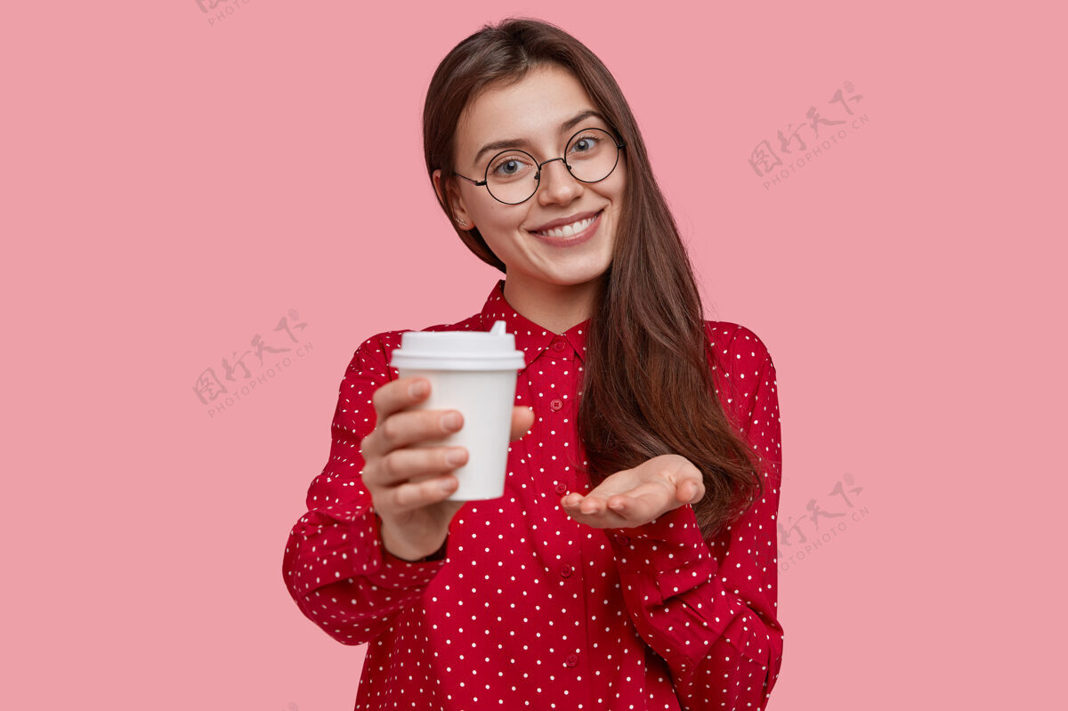 年轻人好色的女人端着一次性咖啡 建议一起喝 戴着眼镜 红色圆点衬衫 歪着头外卖满意的享受