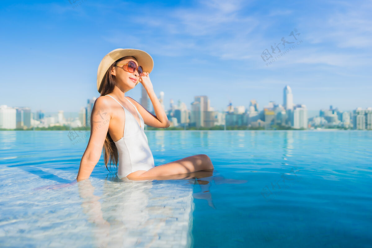 顶部美丽的亚洲年轻女子在户外游泳池周围放松 城市景色尽收眼底中心女性无限