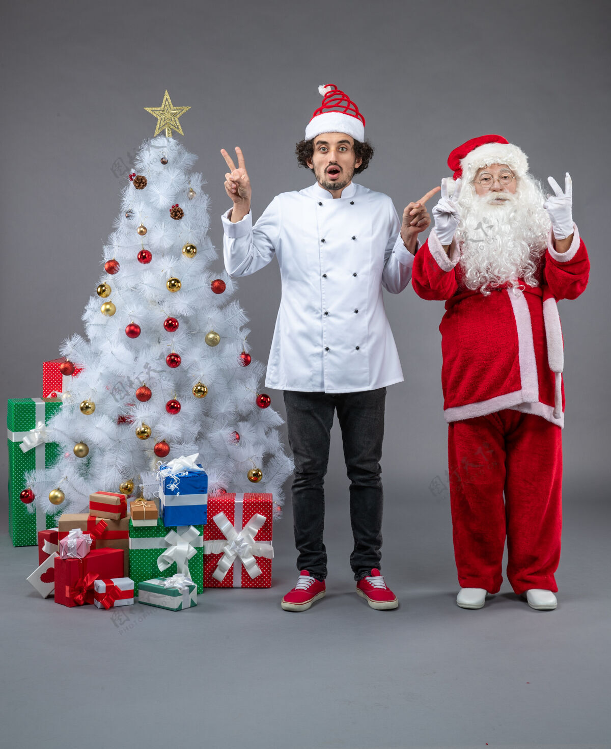 礼物圣诞老人和男厨师在灰色墙上围着圣诞礼物的正视图圣诞庆祝快乐