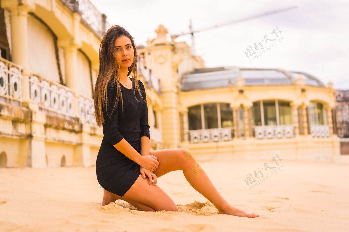 优雅生活方式 一个年轻的黑发白人妇女的肖像 穿着黑色短裙 坐在沙滩上放暑假年轻街道长板