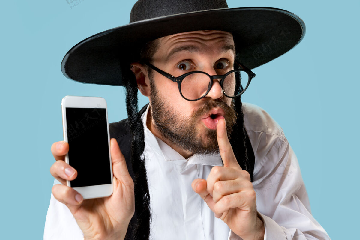 男性一个年轻的东正教犹太男子与手机在工作室的肖像成人犹太人胡须