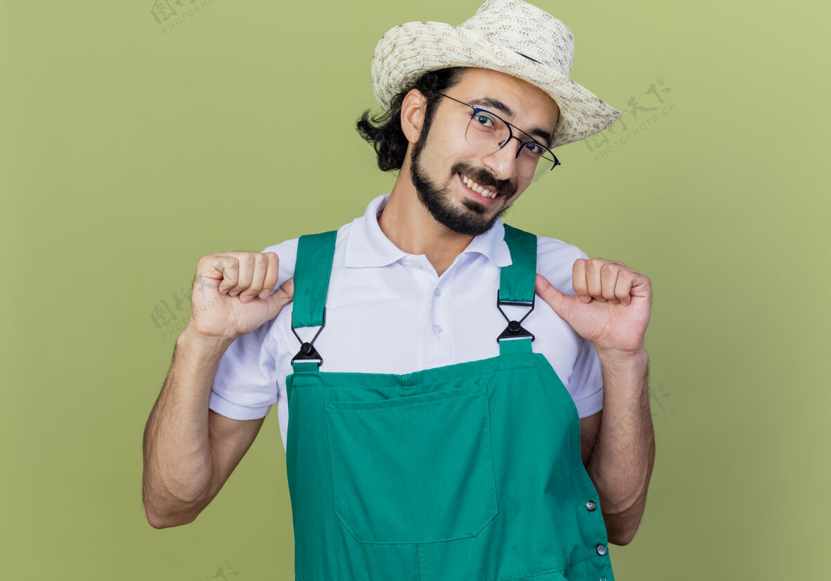 高兴一个穿着连体衣 戴着帽子 满脸胡须的年轻园丁高兴地朝自己微笑着留着胡子高兴光