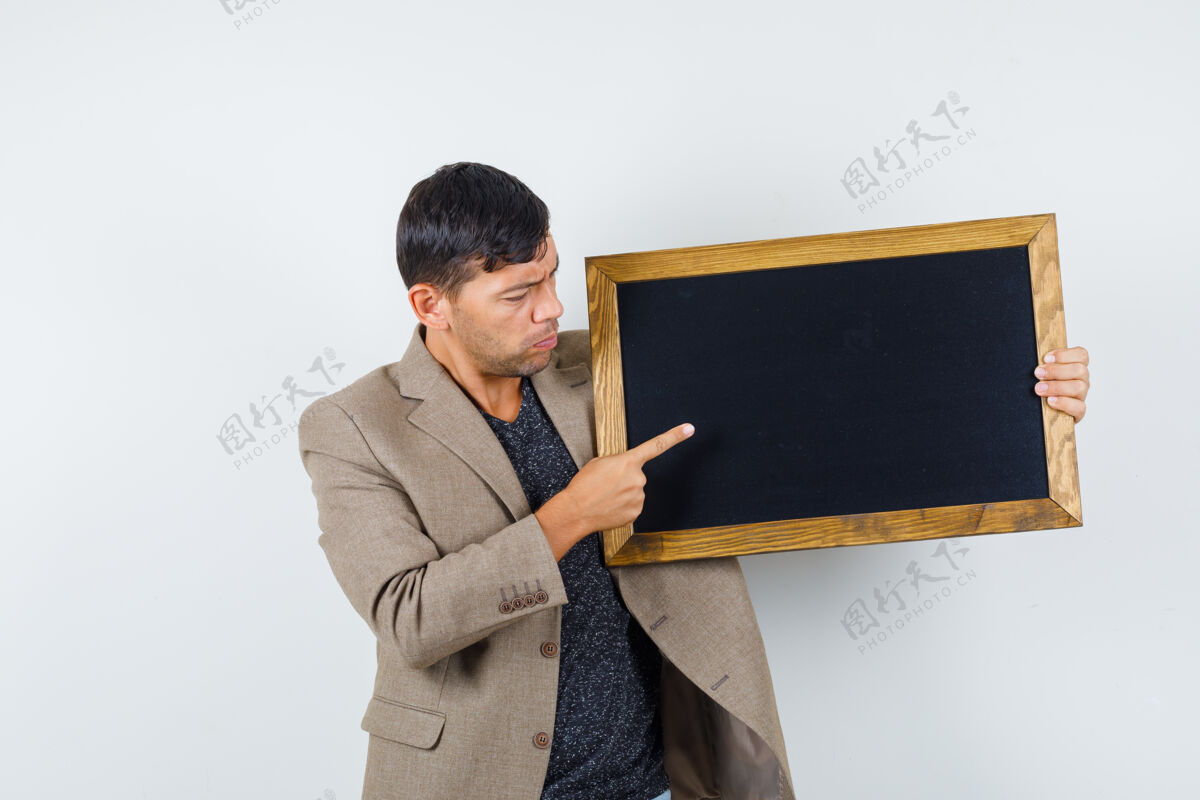 表情身穿灰褐色夹克的年轻男子指着纸板 若有所思地看着前方棕色男人灰色