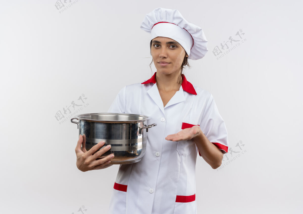 高兴高兴的年轻女厨师穿着厨师制服拿着和点手平底锅在隔离的白色墙壁上复制空间年轻制服女