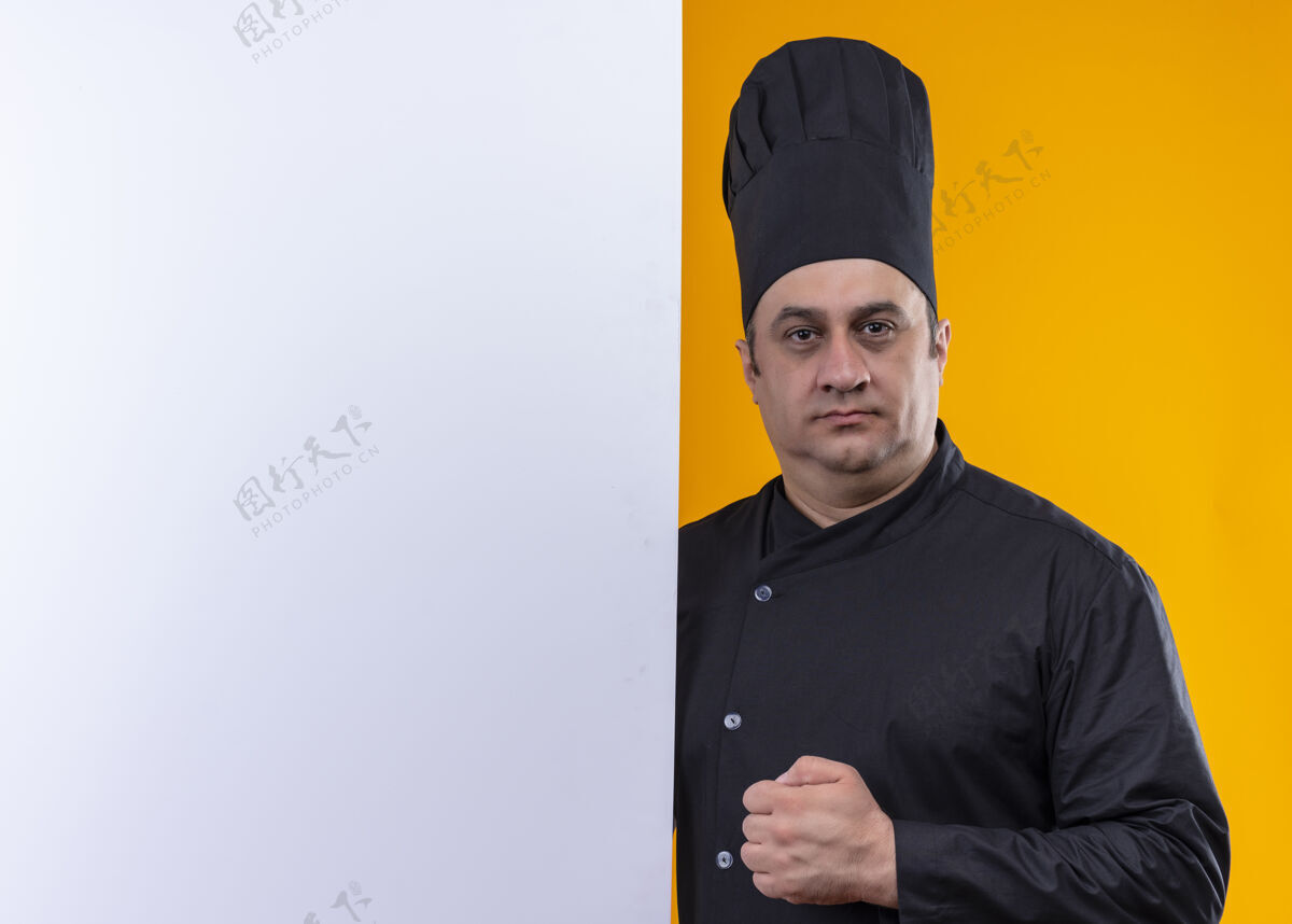 中年自信的中年男厨师 身着厨师制服 手拿白色墙壁 黄色墙壁上有复制空间男自信抱着