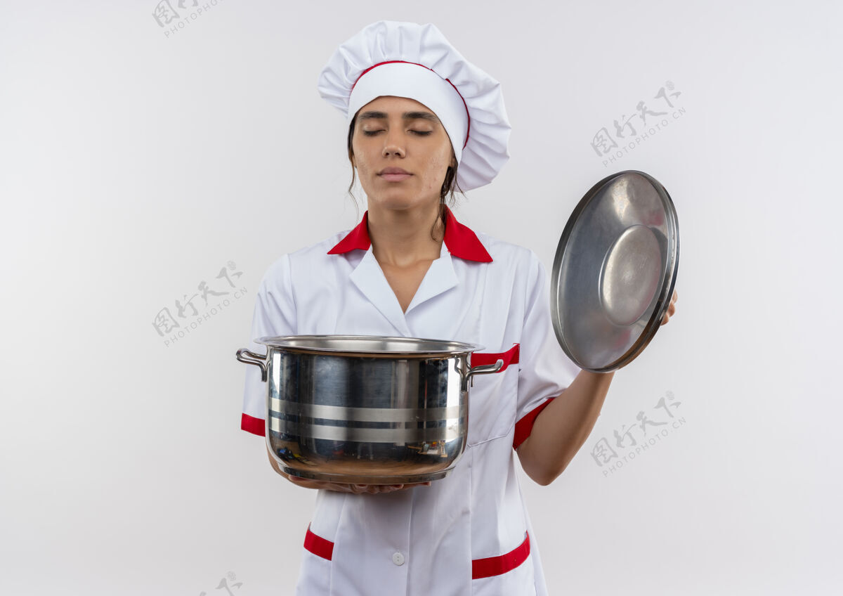 平底锅年轻的女厨师闭着眼睛 穿着厨师制服 手里拿着平底锅和盖子 还有复印空间盖子厨师女