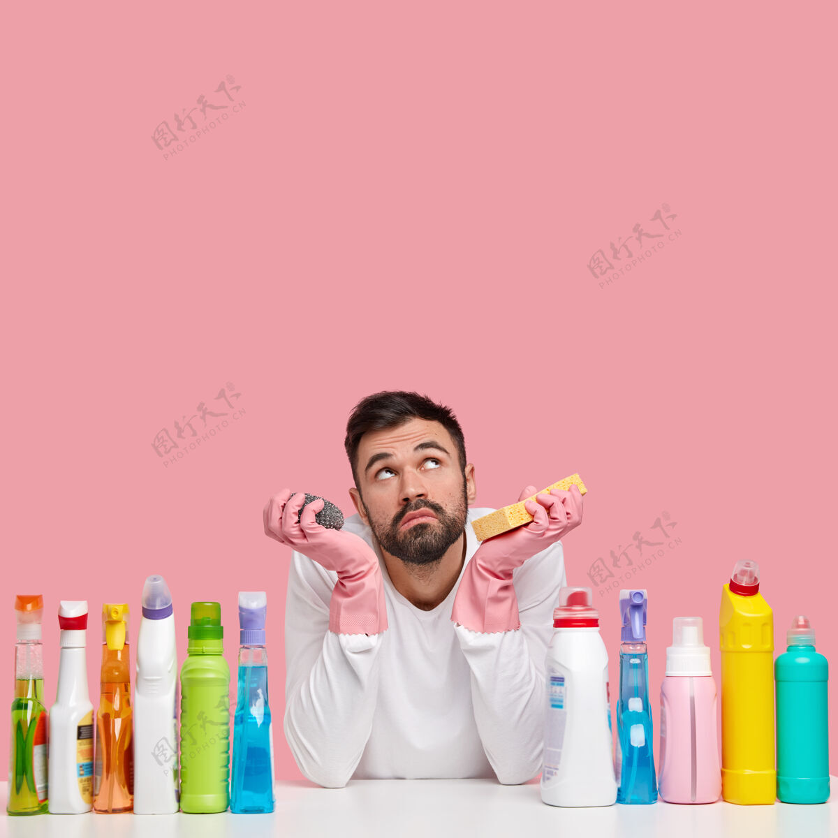 工作不开心的没刮胡子的男人神情悲伤地向上聚焦 想先打扫什么房间 用不同的洗涤剂忙瓶子不安