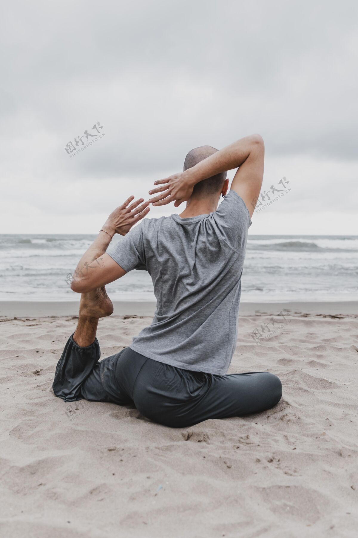 训练海滩上练习瑜伽的男人的后视图专注瑜伽禅宗