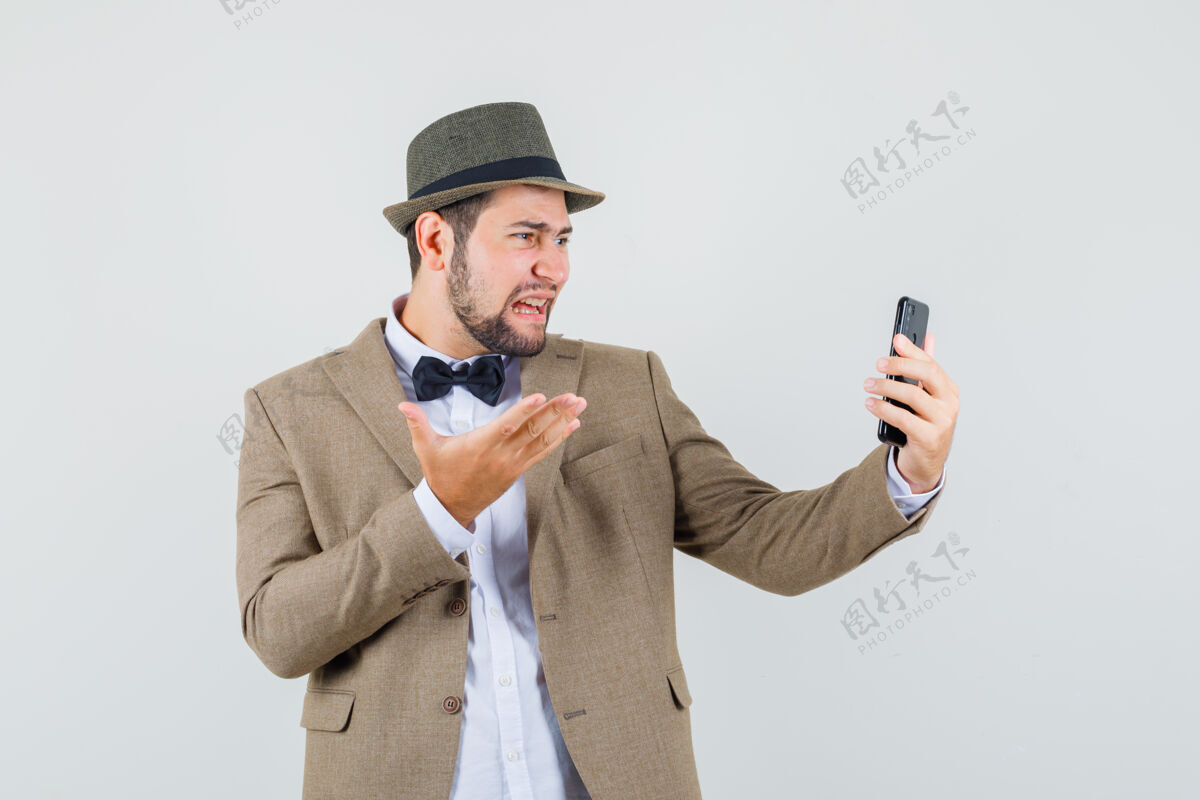 友好穿西装的年轻人 戴着帽子边打电话边喊叫 看上去很沮丧 前视图休闲电话男人