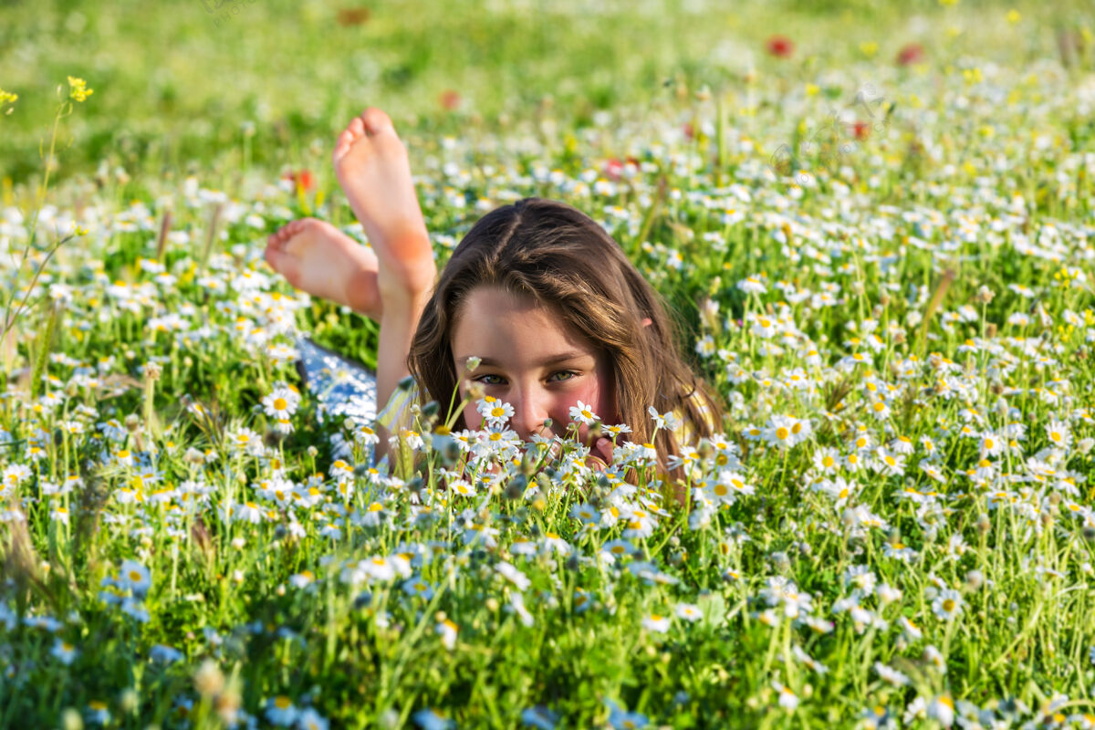 多彩可爱的小女孩躺在盛开的草地上享受明亮花